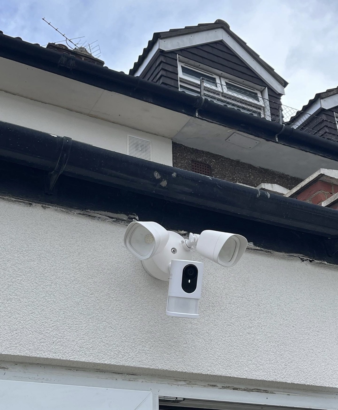 Ring floodlight security camera installed under a roof gutter